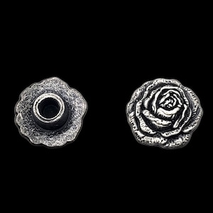 May include: Two silver-toned metal rose-shaped buttons. One button has a hole in the center, the other button is solid.