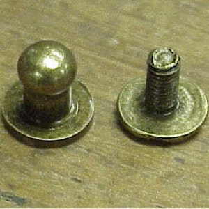 May include: Two antique brass furniture knobs with a round top and a flat base. One knob has a round top and the other has a threaded post.
