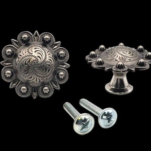 May include: Two silver-toned metal drawer pulls with a decorative floral design. One pull is a round knob with a raised center and the other is a round knob with a raised center and a short stem. Two silver screws are included.