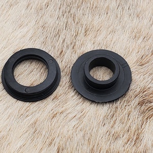 May include: Two black plastic rings, one with a raised lip and the other with a flat surface. Both rings have a central hole.