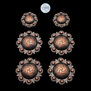 May include: Six circular metal concho buttons arranged in three pairs of varying sizes. Each button features a dark copper-toned center with an engraved swirling pattern, surrounded by a silver-toned border with small raised spherical accents.