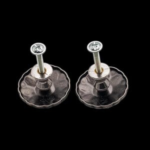 Może przedstawiać: Dwa srebrne gałki do szafek z teksturowaną, ciemnoszarą powierzchnią i falistą krawędzią. Każda gałka ma srebrną śrubę i mały zarys Teksasu. Gałki są ustawione na czarnym tle.