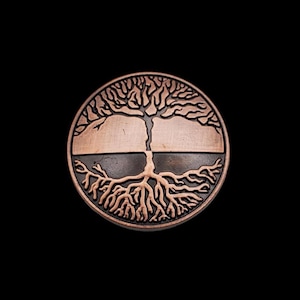 May include: A copper-colored coin with a tree of life design. The tree has a dark brown trunk and branches, and the roots are a lighter shade of copper. The coin is round and has a smooth surface.