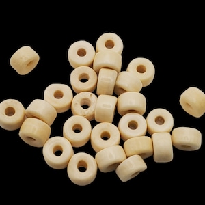 May include: A pile of off-white wooden beads with a hole in the center. The beads are round and have a smooth surface.