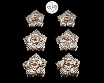May include: Six silver-toned metal flower-shaped conchos arranged in two columns of three. Each piece features a detailed five-petaled floral design with a textured copper-colored center. A circular logo with a Texas outline and the text HAX is centered.