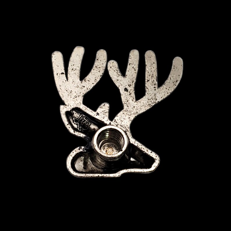May include: Silver metal ornament shaped like a reindeer head with antlers. The ornament has a threaded hole in the bottom for hanging.