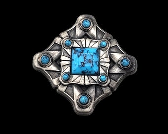 May include: A silver-toned metal belt buckle with a turquoise stone in the center and smaller turquoise stones around the edges.