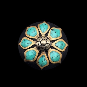May include: A circular knob featuring a black base with a central brass flower motif. The flower has eight petals inlaid with speckled turquoise-colored material, surrounding a small, rounded, segmented brass center piece.