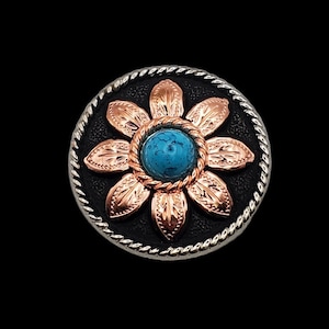 May include: A silver and black button with a copper flower design and a turquoise stone in the center.