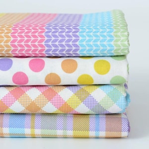 May include: A stack of four folded fabric pieces. The top layer features a multicolored knit-style pattern. The second layer is white with pastel polka dots. The third layer has a pastel gingham check. The bottom layer shows a pastel plaid pattern.