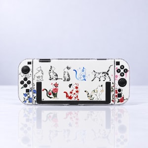 Può includere: Una skin per console di gioco bianca con varie illustrazioni di gatti, inclusi gatti in bianco e nero, un gatto blu con stelle e gatti decorati con foglie d'acero rosse e motivi floreali, insieme a piccole farfalle e fiori.