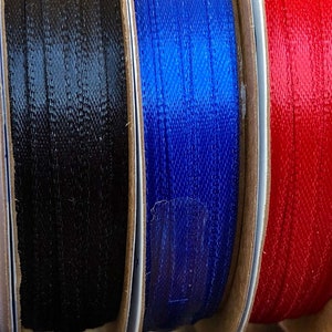 May include: Assortment of spools of ribbon in various colors, including light blue, pink, white, black, blue, red, light pink, purple, and yellow.