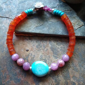 May include: A multi-colored beaded bracelet with orange, pink, and turquoise beads. The bracelet has a silver clasp.