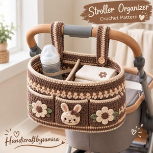 Puede incluir: Un organizador de cochecito de bebé tejido a ganchillo en marrón y crema con tres bolsillos frontales con motivos florales y de conejo. Incluye dos correas con botones de madera, un divisor central y el texto Stroller Organizer Crochet Pattern.
