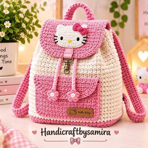 Puede incluir: Una mochila de ganchillo en rosa y crema con una cara de Hello Kitty en la solapa superior, un bolsillo frontal con dos botones en forma de flor, una etiqueta de marca Hello Kitty de cuero marrón y un cierre de metal con correas rosas.
