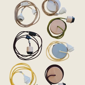 Può includere: Una collezione di lampade etichettate come Baladeuses e Suspensions. Le Baladeuses sono cavi con spina e interruttore in beige, marrone scuro e giallo. Le Suspensions sono lampade da soffitto con basi rotonde in bianco, legno e blu.