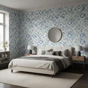 May include: A bedroom featuring wallpaper with a blue and white geometric star pattern, a white upholstered bed with a gray throw blanket, two light wood nightstands with gray lamps, and a round mirror centered on the wall above the bed.