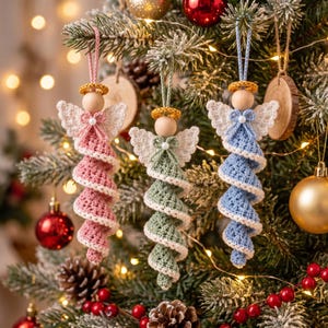 Puede incluir: Tres adornos de ángeles de ganchillo hechos a mano colgados de un árbol. Cada ángel tiene una cabeza de cuenta de madera, un halo dorado, alas blancas, un pequeño lazo con una perla central y un vestido en espiral rosa, verde o azul claro.
