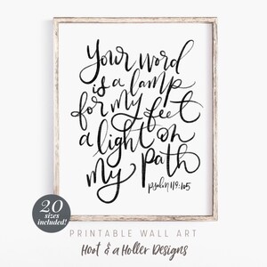 May include: A framed print featuring the quote "Your word is a lamp for my feet, a light on my path" in black calligraphy on a white backdrop. The print also includes the Bible verse Psalm 119:105.
