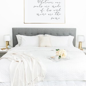 May include: A white bed with a white blanket and a white pillow. A gold framed print with the text "Whatever our souls are made of, his and mine are the same" hangs above the bed.
