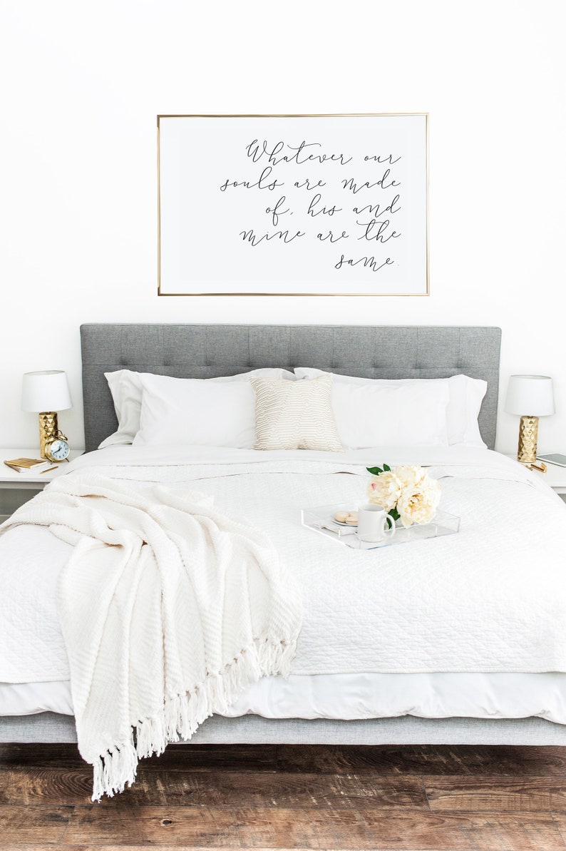 May include: A white bed with a white blanket and a white pillow. A gold framed print with the text "Whatever our souls are made of, his and mine are the same" hangs above the bed.