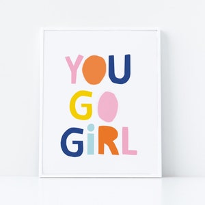 以下が含まれることがあります： 白い額縁に入ったプリントで、"YOU GO GIRL"という文字がカラフルな切り抜き文字で書かれています。文字は青、オレンジ、ピンク、黄色の色合いです。