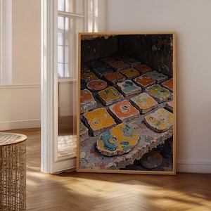 May include: A framed rectangular wall art print featuring a high-angle view of numerous square and circular tiles arranged in a grid. The tiles display a textured, weathered appearance with a palette of yellow, orange, blue, and grey paint splatters.