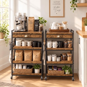 May include: Two industrial-style rolling kitchen carts with black metal frames and brown wood-grain shelves. The carts feature drawers, multiple tiers holding coffee machines, bags of coffee beans, white mugs with text, glass jars, and woven baskets.