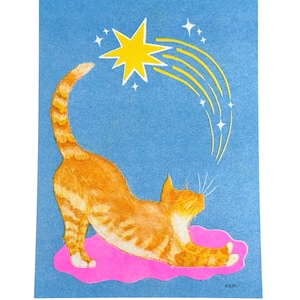 May include: A rectangular print on blue paper featuring an orange tabby cat stretching on a pink cloud. Above the cat, a yellow star with white trailing lines and small white star accents appears. The artist signature KAM is in the bottom right.