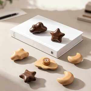 May include: A collection of wooden cabinet knobs in various shapes including stars, clouds, and crescent moons. The knobs are crafted from light and dark wood, featuring smooth, rounded edges. One cloud-shaped knob shows a central metal mounting hole.
