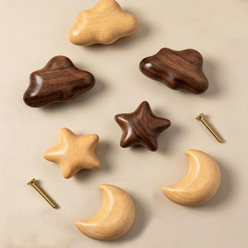 May include: A collection of wooden cabinet knobs in the shapes of clouds, stars, and moons, featuring both light-toned beech wood and dark-toned walnut wood finishes. Two metal mounting screws are included alongside the seven wooden shapes.