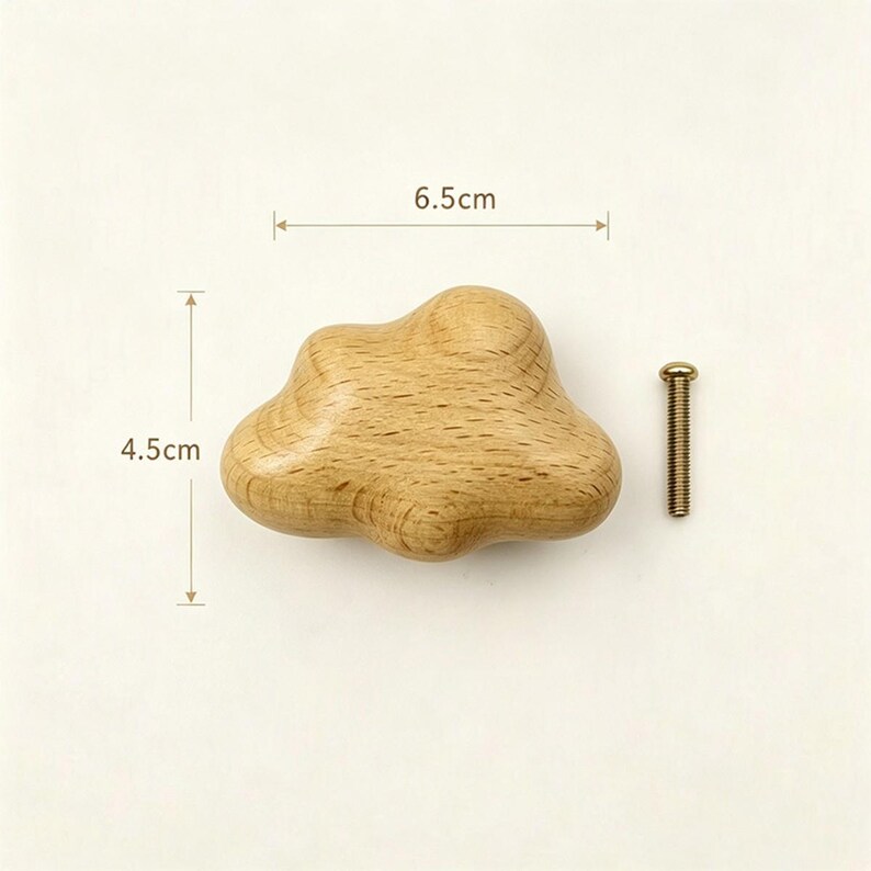 May include: A light brown wooden cabinet knob shaped like a cloud, featuring a smooth, natural wood grain finish. The knob measures 6.5 cm in width and 4.5 cm in height, accompanied by a single silver-toned metal mounting screw for installation.