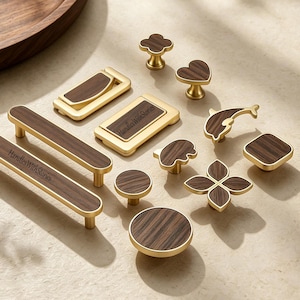 May include: A collection of cabinet hardware featuring gold-toned metal frames with dark wood grain inlays. The set includes various shapes such as rectangular pulls, round knobs, a heart, a dolphin, and floral designs, with HandlesWithStories text.