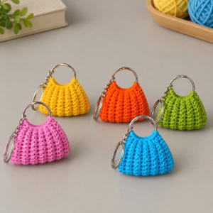 May include: Five miniature crochet handbags in bright yellow, orange, lime green, pink, and blue. Each small bag features a textured, ribbed stitch pattern, a circular silver-tone metal handle, and a matching silver-tone metal keychain ring.