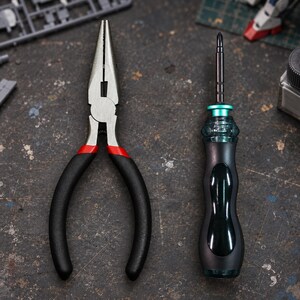 Peut inclure: Une pince à bec effilé avec des mâchoires en métal argenté et des poignées en caoutchouc noir avec des accents rouges, placée à côté d'un tournevis de précision avec un manche ergonomique noir, une bague turquoise et une tige fine en métal.