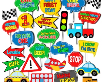 May include: A set of 18 colorful photo booth props with a transportation theme. The props feature phrases like "One Today!" and "Happy First B'day" as well as images of cars, trains, airplanes, and traffic signs.