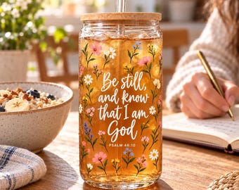May include: A clear glass tumbler with a bamboo lid and a glass straw, filled with amber liquid. The exterior features a colorful floral pattern and the white text: Be still, and know that I am God, PSALM 46:10.
