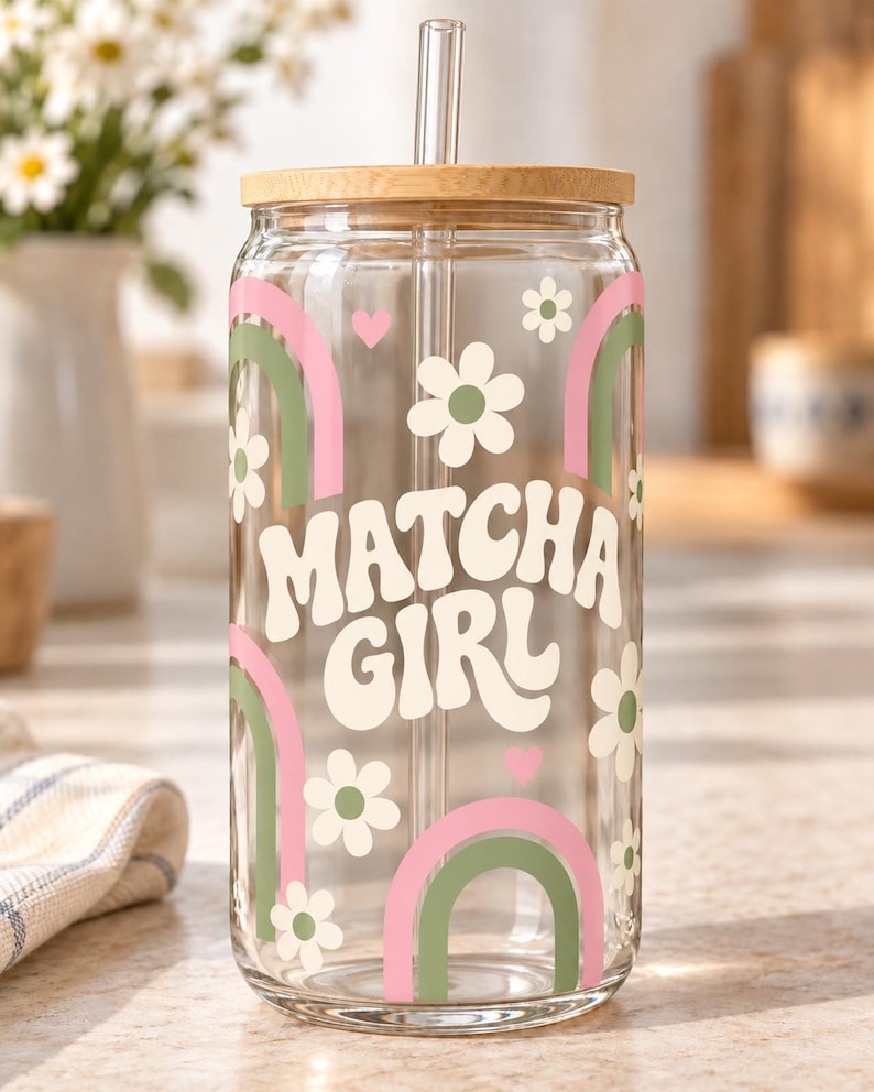 Digital mockup of a clear glass cup showing Matcha Girl lettering, pink and green rainbows and cream daisies. Bamboo lid shown.