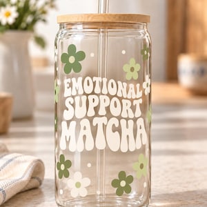 Digital mockup of a clear glass cup showing Emotional Support Matcha lettering with green and ivory flowers. Bamboo lid shown.