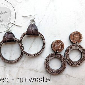 May include: Two pairs of brown leather earrings with a circle design. The earrings are nested together, with the smaller pair inside the larger pair. The text "nested - no waste!" is written below the earrings.