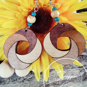 May include: A pair of wooden earrings with a unique knot design. The earrings are made of three different shades of wood, creating a layered effect. The earrings are accented with turquoise and wooden beads.
