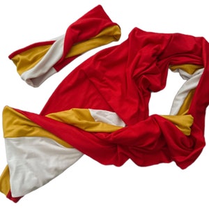 K&ouml;nnte beinhalten: Ein rotes, gelbes und wei&szlig;es Schal- und Stirnband-Set. Der Schal ist lang und flie&szlig;end, mit Abschnitten aus rotem, gelbem und wei&szlig;em Stoff. Das Stirnband hat ein gedrehtes Design und weist ebenfalls das gleiche Farbschema auf.