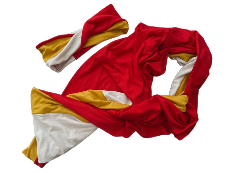 K&ouml;nnte beinhalten: Ein rotes, gelbes und wei&szlig;es Schal- und Stirnband-Set. Der Schal ist lang und flie&szlig;end, mit Abschnitten aus rotem, gelbem und wei&szlig;em Stoff. Das Stirnband hat ein gedrehtes Design und weist ebenfalls das gleiche Farbschema auf.