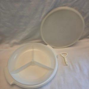 May include: A white circular serving tray with three internal compartments, featuring two side handles. The set includes a matching circular lid and a small, T-shaped white plastic tool used for assembly or locking the central divider section.