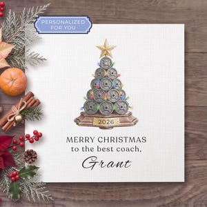 May include: A square greeting card featuring a Christmas tree illustration made of stacked grey weight plates, topped with a gold star and decorated with colorful lights. The base displays the year 2026. Text reads: MERRY CHRISTMAS to the best coach, Grant.