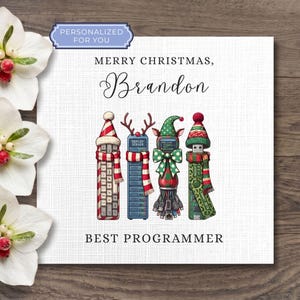 May include: A square greeting card with a white textured background featuring the text "MERRY CHRISTMAS, BRANDON" and "BEST PROGRAMMER". The illustration shows four tech items dressed in festive hats and scarves, including a server and USB drive.