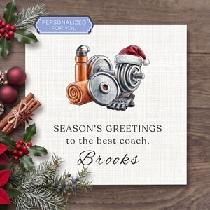 May include: A square greeting card featuring a watercolor illustration of a copper water bottle, a rolled orange towel, and silver dumbbells wearing a red Santa hat. The text reads: PERSONALIZED FOR YOU, SEASON'S GREETINGS to the best coach, Brooks.