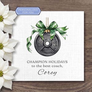 May include: A square card featuring a watercolor illustration of a black 45 lb weight plate hanging from a green ribbon bow. The text reads "CHAMPION HOLIDAYS to the best coach, Corey". A blue label at the top says "PERSONALIZED FOR YOU".