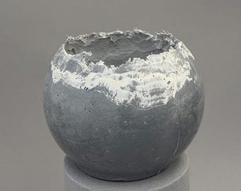 Small medium-gray concrete vessel sculpture. Sustainable. Live edge. Bowl with a natural shiny outside surface. Wabi-sabi style.