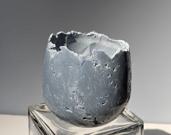 Small gray concrete vessel sculpture. Sustainable. Live edge. Bowl has a natural shiny outside surface. Wabi-sabi style.